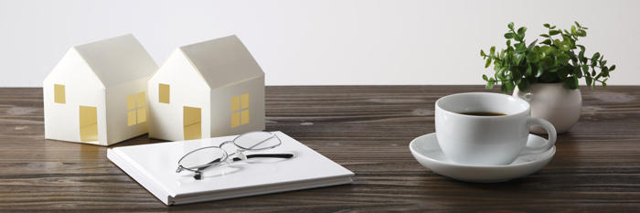 Model house on a desk next to glasses and documents